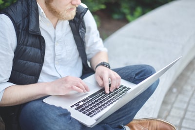 坐在长凳上使用MacBook的人